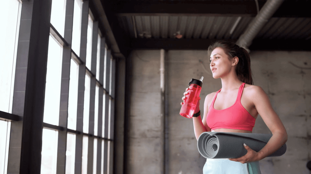 Das Mädchen setzt eine Flasche Wasser und einen Teppich